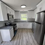 Interior view of a clean, modern kitchen with white cabinetry and stainless steel appliances.